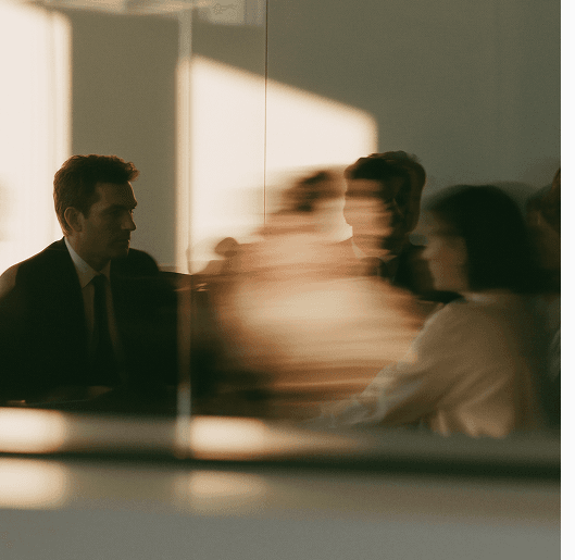 A meeting seen through glass, figures softened by reflection